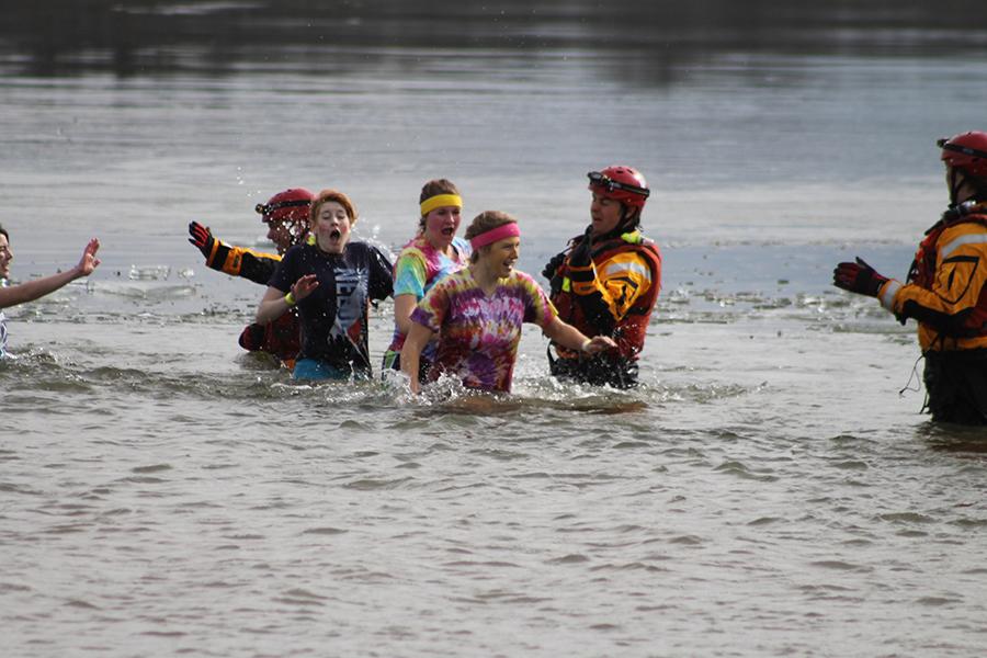 Running for the shore, Seniors Alex Scavuzzo and Rebecca Millard, and Junior Kylee Reichman trudge through the last part of the water to complete their plunge at Longview Lake on Saturday, Jan. 25.