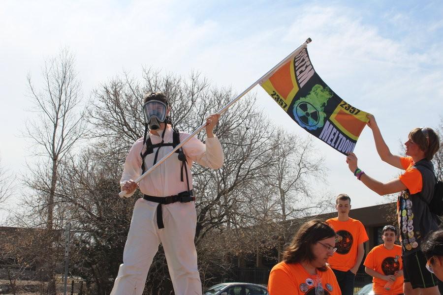 Wearing the team hazmat suit and holding the flag, Junior John Kampe was the mechanical lead this year and last year, and did most of the mechanical work his freshmen year.