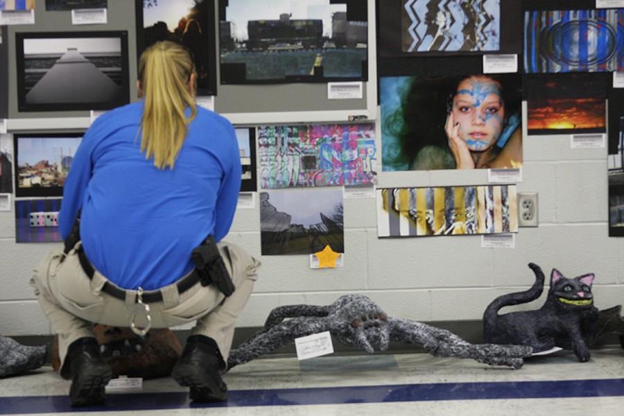 A visitor looks at the different photographs on the wall done by photo journalism 1 and photo journalism 2 students.